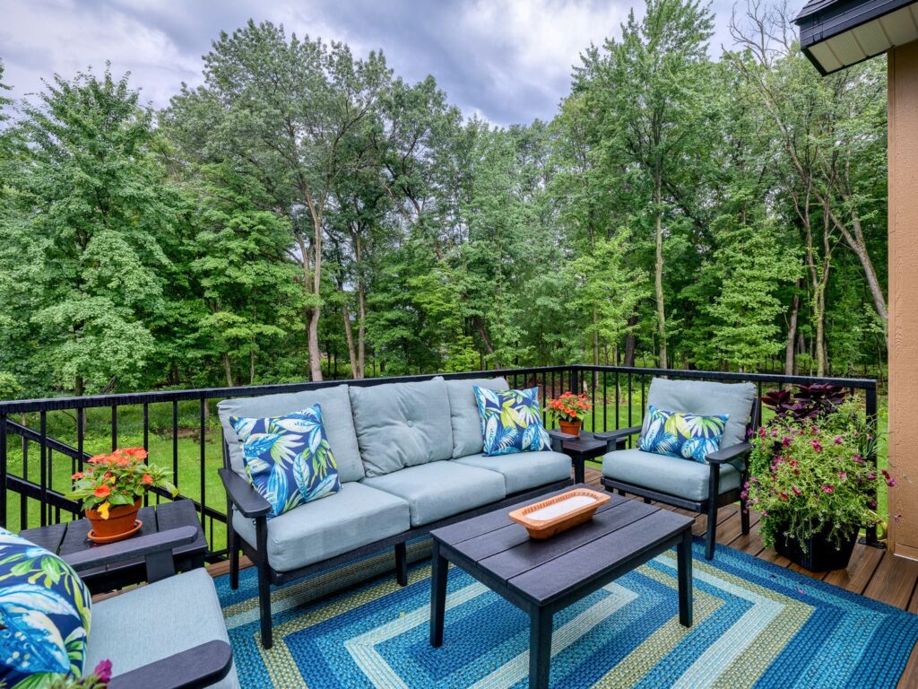 Bright tropical porch design in wooded private backyard. Design by Room Reimagined Design Twin Cities Interior Design for Parade of Homes 2025